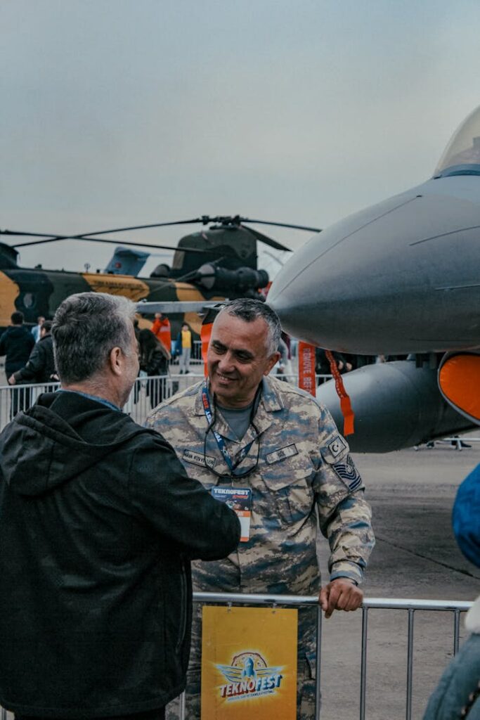 Military personnel in uniform at İstanbul air show engaging with attendee.